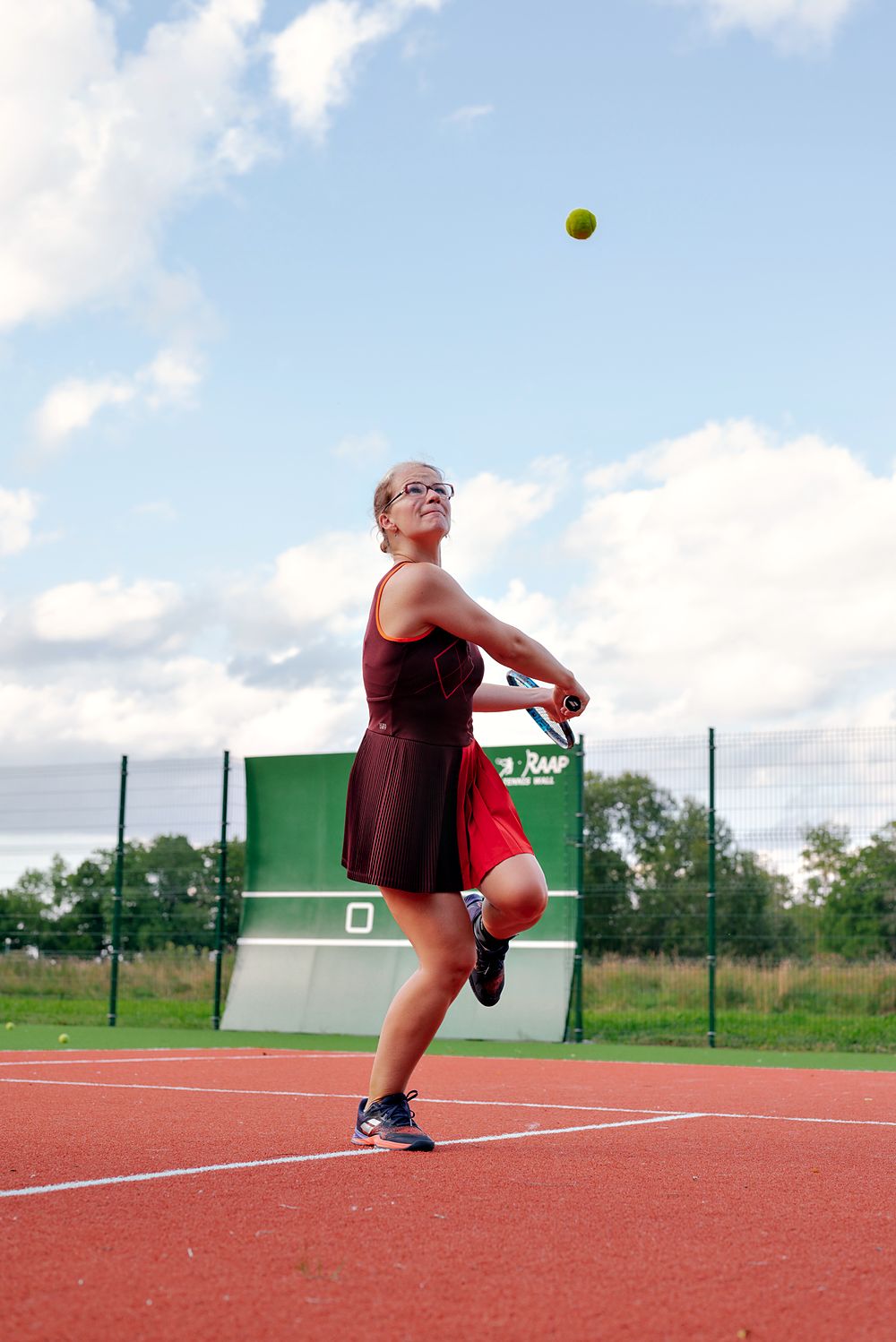 Ilona hitting a backhand under a blue sky